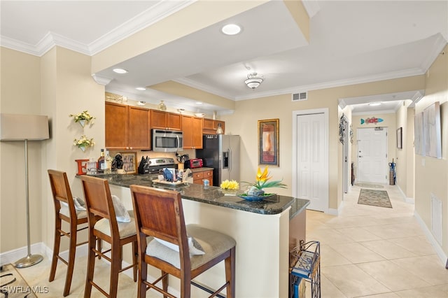 28750 Trails Edge Blvd Unit 303, Bonita Springs, FL 34134 - kitchen with appliances with stainless steel finishes, a peninsula, brown cabinets, a kitchen breakfast bar, and light tile patterned floors