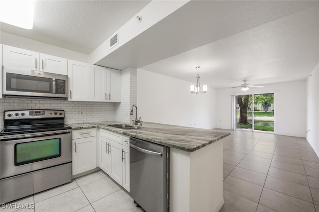 8244 Key Royal Cir Unit 615, Naples, FL 34119 - kitchen with stainless steel appliances, a peninsula, white cabinets, light tile patterned floors, and a textured ceiling