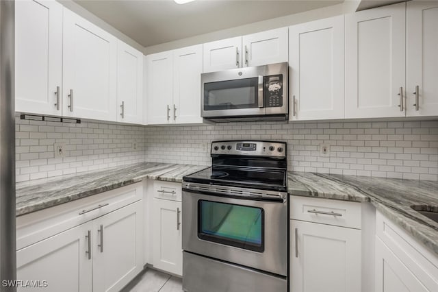 8244 Key Royal Cir Unit 615, Naples, FL 34119 - kitchen with stainless steel appliances, white cabinets, tasteful backsplash, and light stone countertops