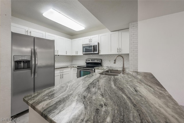 8244 Key Royal Cir Unit 615, Naples, FL 34119 - kitchen featuring appliances with stainless steel finishes, a peninsula, stone countertops, decorative backsplash, and white cabinets