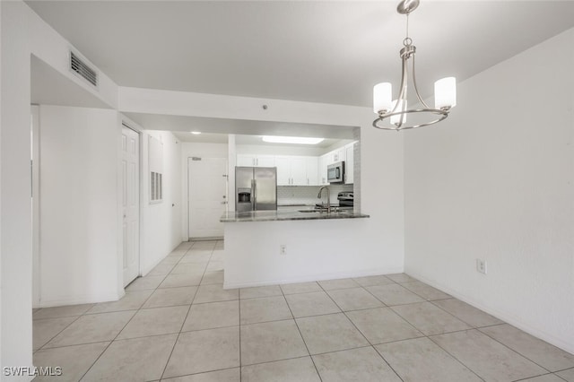 8244 Key Royal Cir Unit 615, Naples, FL 34119 - kitchen featuring appliances with stainless steel finishes, white cabinets, light tile patterned floors, a chandelier, and a peninsula