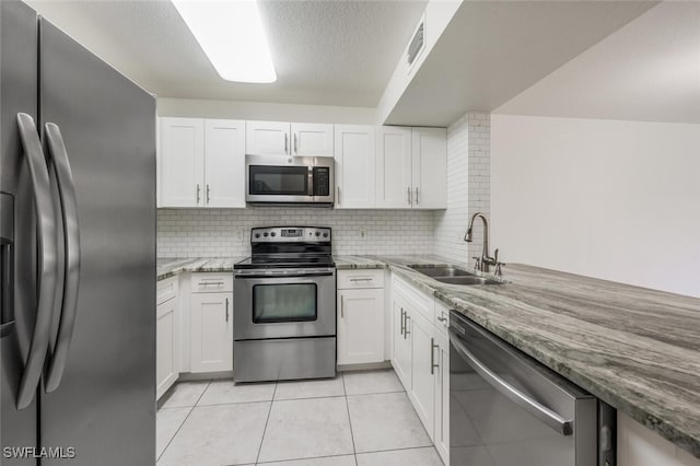 8244 Key Royal Cir Unit 615, Naples, FL 34119 - kitchen featuring appliances with stainless steel finishes, light stone counters, white cabinets, decorative backsplash, and a textured ceiling