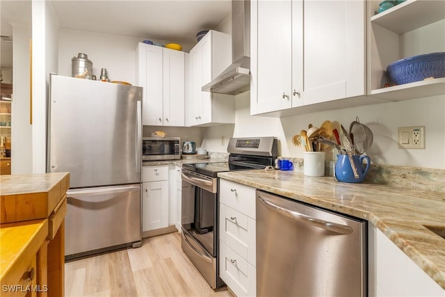 5228 Stringfellow Rd, Saint James City, FL 33956 - kitchen featuring stainless steel appliances, wall chimney range hood, white cabinetry, light wood-style floors, and light stone countertops