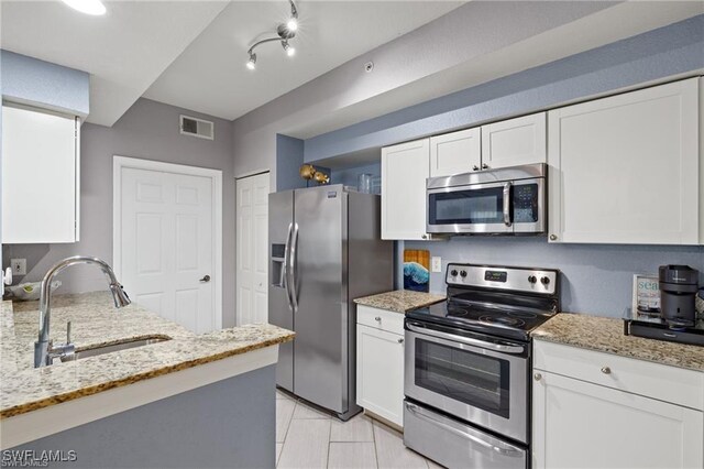 4635 Saint Croix Ln Unit 1222, Naples, FL 34109 - kitchen with stainless steel appliances, a sink, white cabinets, light stone countertops, and light tile patterned floors