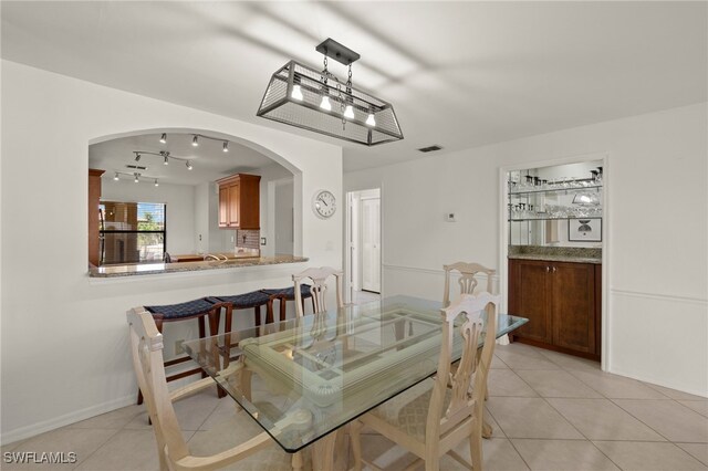 12170 Kelly Sands Way Unit 721, Fort Myers, FL 33908 - dining room featuring arched walkways, light tile patterned floors, track lighting, and baseboards