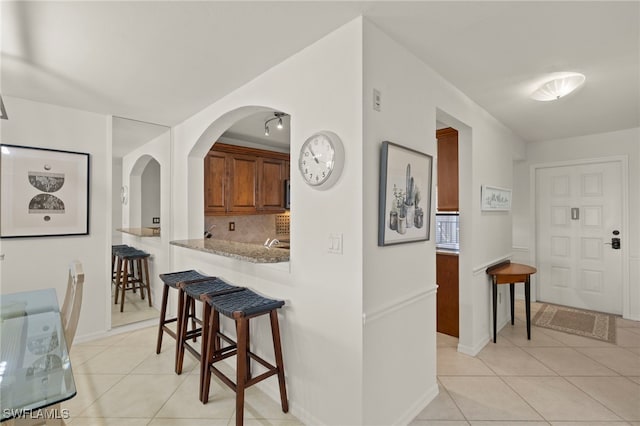 12170 Kelly Sands Way Unit 721, Fort Myers, FL 33908 - hallway with light tile patterned flooring, arched walkways, and baseboards
