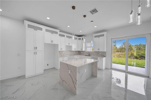 420-422 Grant Blvd, Lehigh Acres, FL 33974 - kitchen with light marble finish flooring, a kitchen island, recessed lighting, glass insert cabinets, and light stone countertops