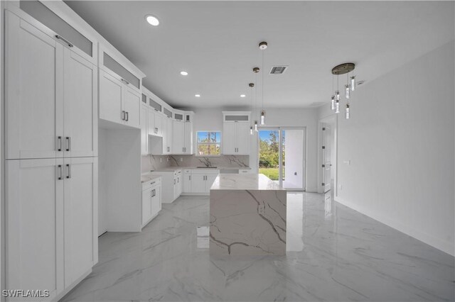 420-422 Grant Blvd, Lehigh Acres, FL 33974 - kitchen featuring light marble finish floors, glass insert cabinets, a center island, light stone counters, and white cabinetry