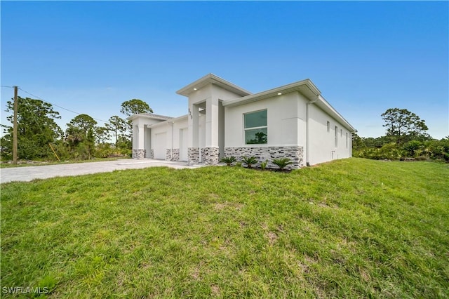 420-422 Grant Blvd, Lehigh Acres, FL 33974 - view of front of house with driveway, stucco siding, a front yard, stone siding, and an attached garage