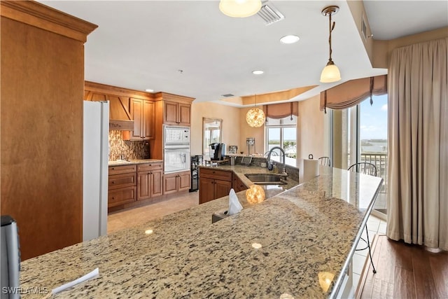 6021 Silver King Blvd Unit 302, Cape Coral, FL 33914 - kitchen featuring brown cabinets, white appliances, premium range hood, a breakfast bar area, and recessed lighting