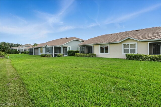 2232 Carnaby Ct, Lehigh Acres, FL 33973 - back of house with a lawn, a sunroom, a tile roof, and stucco siding