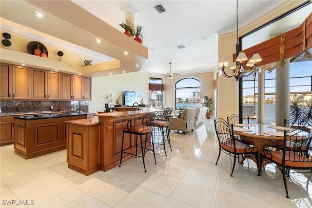 431 Palm Ct, Naples, FL 34108 - kitchen featuring a large island, crown molding, brown cabinets, decorative backsplash, and a chandelier