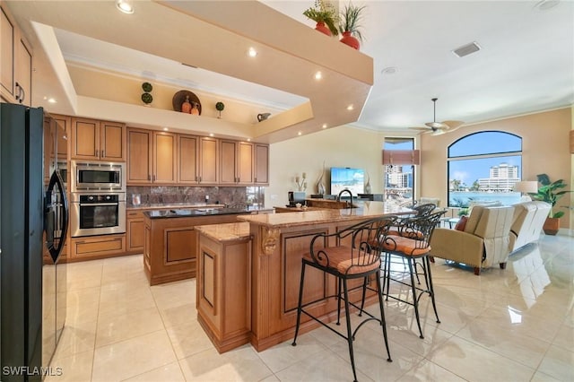 431 Palm Ct, Naples, FL 34108 - kitchen with appliances with stainless steel finishes, a spacious island, brown cabinets, decorative backsplash, and open floor plan