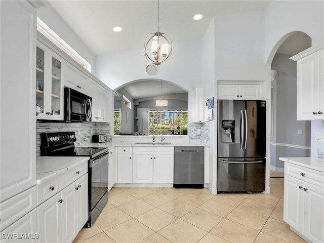 8627 Ibis Cove Cir, Naples, FL 34119 - kitchen with black appliances, arched walkways, decorative backsplash, glass insert cabinets, and light countertops