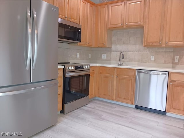 7725 Woodbrook Cir Unit 3504, Naples, FL 34104 - kitchen with stainless steel appliances, light countertops, light wood finished floors, tasteful backsplash, and light brown cabinetry