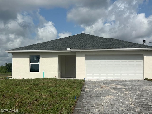 658 Ivanhoe Ave S, Lehigh Acres, FL 33974 - ranch-style home featuring stucco siding, decorative driveway, a shingled roof, an attached garage, and a front yard