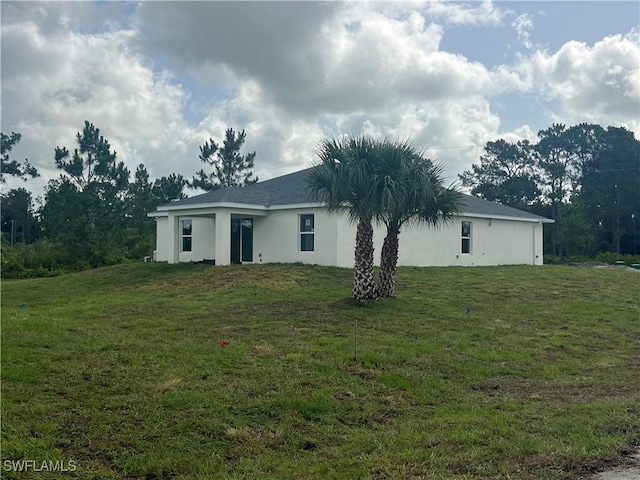 658 Ivanhoe Ave S, Lehigh Acres, FL 33974 - back of property featuring stucco siding and a lawn