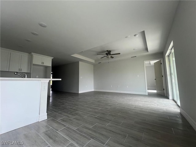 658 Ivanhoe Ave S, Lehigh Acres, FL 33974 - unfurnished living room featuring a tray ceiling, a ceiling fan, baseboards, and wood finish floors