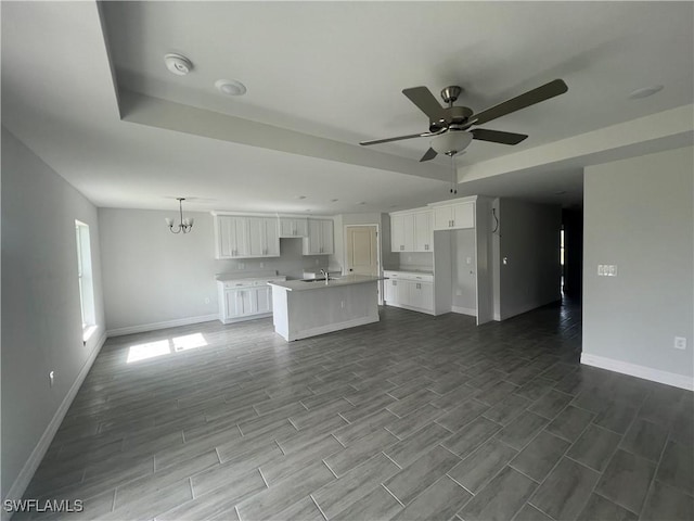 658 Ivanhoe Ave S, Lehigh Acres, FL 33974 - unfurnished living room with baseboards, ceiling fan, dark wood-type flooring, a sink, and a chandelier