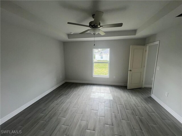 658 Ivanhoe Ave S, Lehigh Acres, FL 33974 - empty room featuring dark wood-style flooring, a tray ceiling, baseboards, and ceiling fan