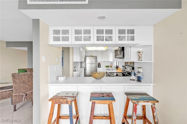 26235 Hickory Blvd Unit 9A, Bonita Springs, FL 34134 - kitchen featuring stainless steel appliances, glass insert cabinets, a peninsula, light countertops, and backsplash