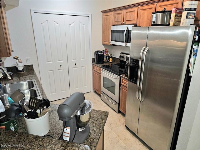 12975 Positano Cir Unit 104, Naples, FL 34105 - kitchen featuring appliances with stainless steel finishes, dark countertops, and brown cabinetry