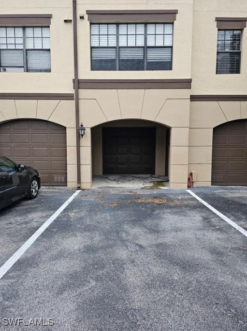 12975 Positano Cir Unit 104, Naples, FL 34105 - view of front facade with stucco siding and an attached garage
