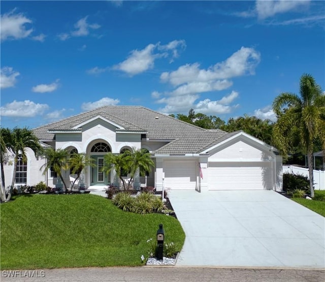 17091 Laurelin Ct, North Fort Myers, FL 33917 - mediterranean / spanish-style house with a front lawn, an attached garage, driveway, a tiled roof, and stucco siding