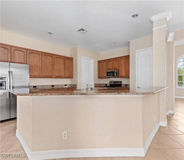 17091 Laurelin Ct, North Fort Myers, FL 33917 - kitchen with appliances with stainless steel finishes, stone countertops, brown cabinetry, light tile patterned floors, and recessed lighting