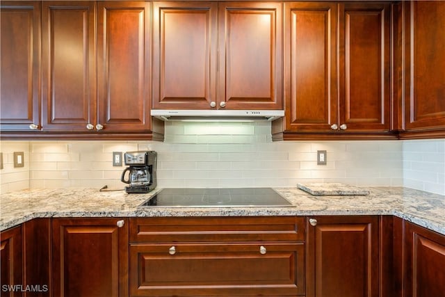 1050 Borghese Ln Unit 605, Naples, FL 34114 - kitchen featuring black electric stovetop, backsplash, light stone countertops, and reddish brown cabinets
