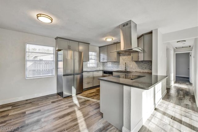 152 Prospect Ave, Fort Myers, FL 33905 - kitchen featuring stainless steel appliances, wall chimney range hood, gray cabinets, a peninsula, and wood finished floors