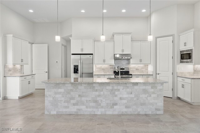 3318 NW 1st Ter, Cape Coral, FL 33993 - kitchen with appliances with stainless steel finishes, a towering ceiling, under cabinet range hood, tasteful backsplash, and a kitchen island with sink