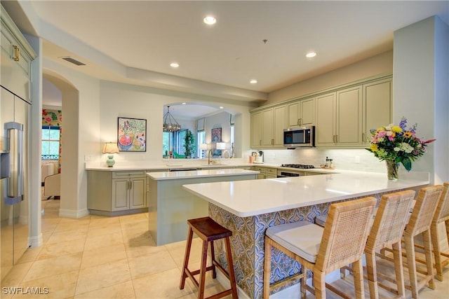 2855 Tiburon Blvd E Unit 102, Naples, FL 34109 - kitchen with stainless steel microwave, arched walkways, a peninsula, backsplash, and light countertops