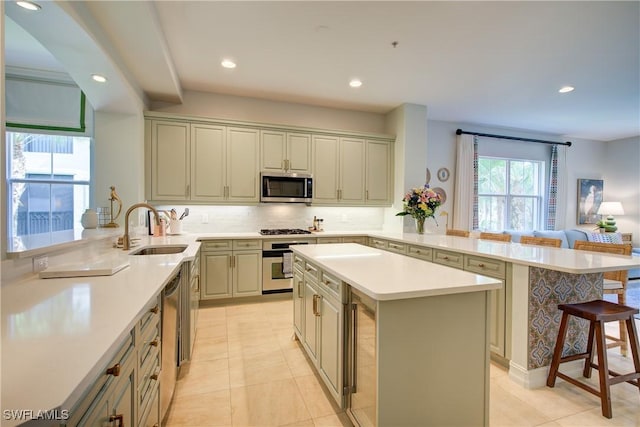 2855 Tiburon Blvd E Unit 102, Naples, FL 34109 - kitchen featuring a peninsula, stainless steel appliances, a kitchen breakfast bar, a center island, and tasteful backsplash