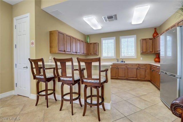 7327 Acorn Way, Naples, FL 34119 - kitchen with freestanding refrigerator, a sink, light countertops, brown cabinets, and a breakfast bar area