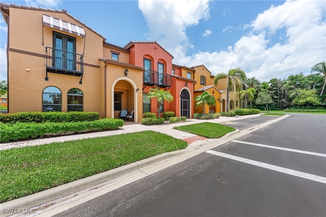 9063 Capistrano St N Unit 4401, Naples, FL 34113 - mediterranean / spanish house featuring a balcony, stucco siding, uncovered parking, a tiled roof, and a front lawn