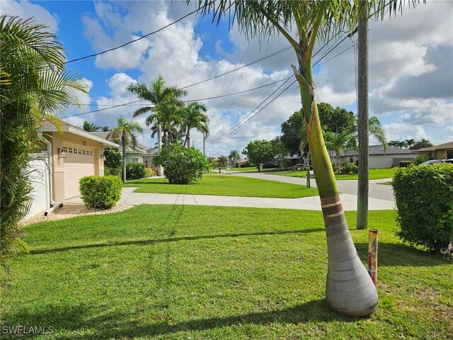 3616 SW 1st Pl, Cape Coral, FL 33914 - view of grassy yard featuring an attached garage and concrete driveway