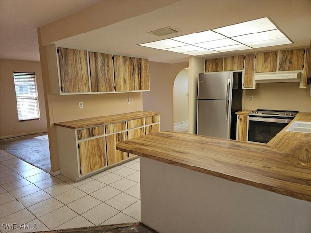 3616 SW 1st Pl, Cape Coral, FL 33914 - kitchen featuring stainless steel appliances, arched walkways, butcher block countertops, under cabinet range hood, and light tile patterned floors