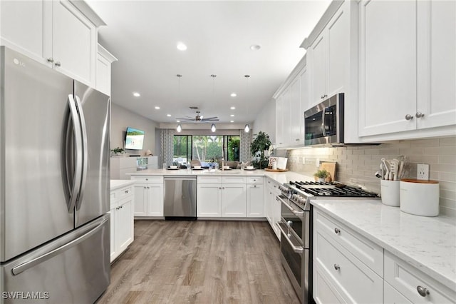 4119 Zelkova Ct, Naples, FL 34119 - kitchen with stainless steel appliances, a ceiling fan, light wood finished floors, backsplash, and white cabinetry