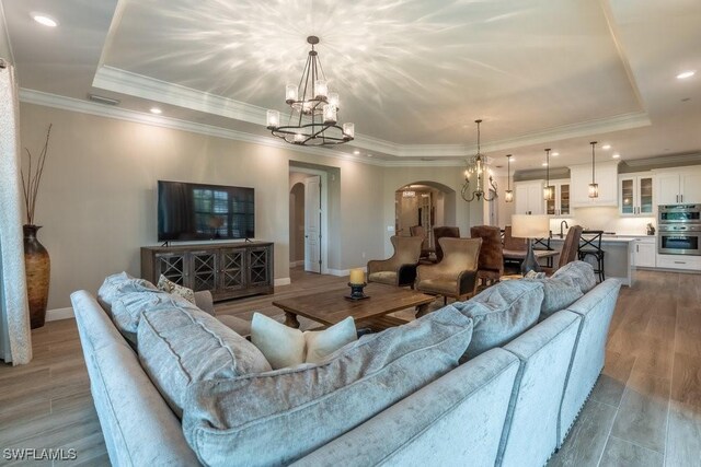 16375 Viansa Way Unit 102, Naples, FL 34110 - living area with a raised ceiling, a chandelier, arched walkways, recessed lighting, and crown molding
