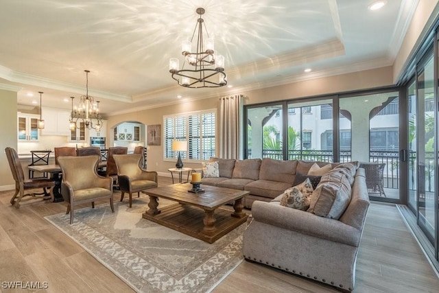 16375 Viansa Way Unit 102, Naples, FL 34110 - living room with a chandelier, a tray ceiling, arched walkways, light wood finished floors, and crown molding