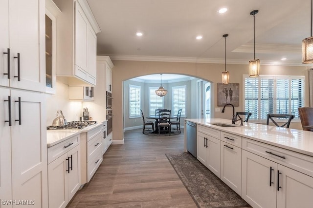 16375 Viansa Way Unit 102, Naples, FL 34110 - kitchen with arched walkways, appliances with stainless steel finishes, white cabinetry, wood finished floors, and glass insert cabinets