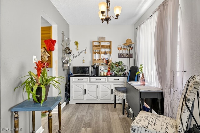 3291 Royal Canadian Trce Unit 3, Fort Myers, FL 33907 - kitchen featuring light wood finished floors, a chandelier, dark countertops, white cabinetry, and stainless steel microwave