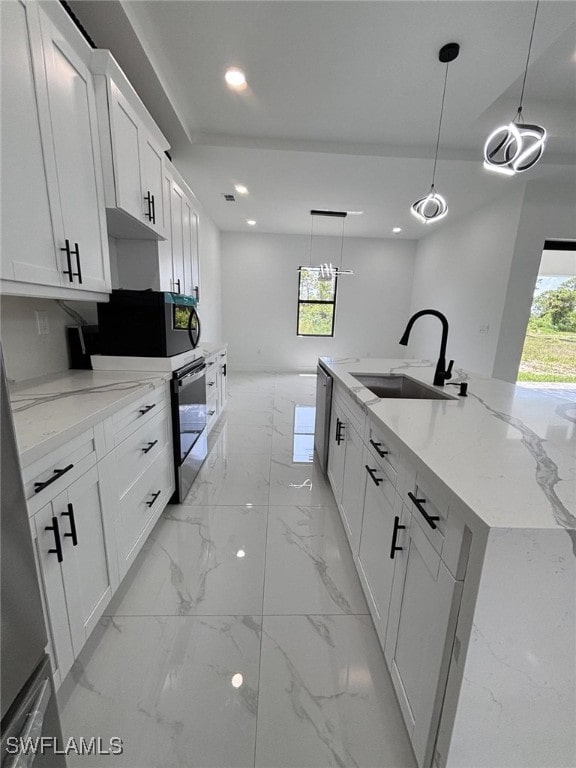 2909 Dora Ave N, Lehigh Acres, FL 33971 - kitchen with recessed lighting, white cabinetry, light marble finish flooring, decorative light fixtures, and light stone counters