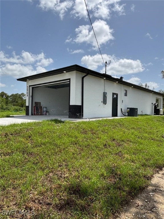 2909 Dora Ave N, Lehigh Acres, FL 33971 - view of property exterior featuring stucco siding, an attached garage, and a lawn