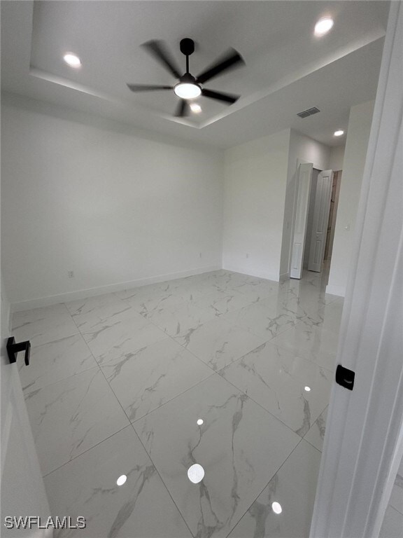 2909 Dora Ave N, Lehigh Acres, FL 33971 - spare room with a raised ceiling, light marble finish flooring, ceiling fan, and recessed lighting