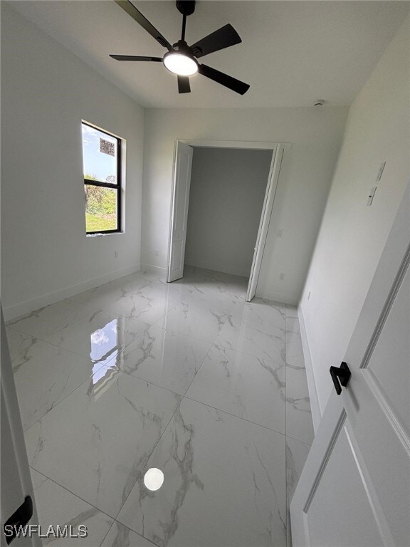 2909 Dora Ave N, Lehigh Acres, FL 33971 - unfurnished bedroom with light marble finish flooring and ceiling fan