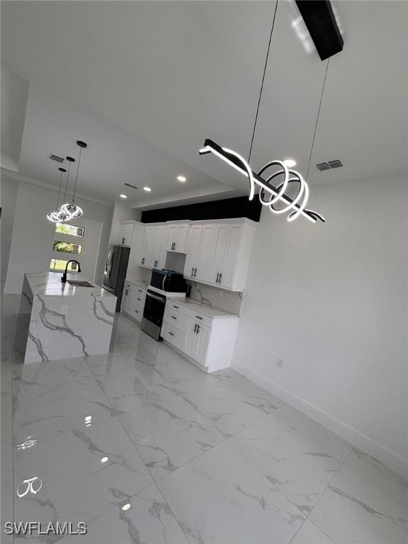 2909 Dora Ave N, Lehigh Acres, FL 33971 - kitchen with stove, recessed lighting, freestanding refrigerator, white cabinets, and light stone countertops