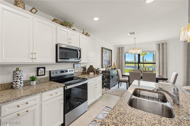 6334 Achievement Ave, Ave Maria, FL 34142 - kitchen with stainless steel appliances, a sink, white cabinets, a chandelier, and pendant lighting