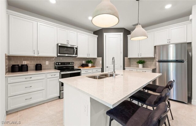 3740 Passion Vine Dr, Alva, FL 33920 - kitchen with appliances with stainless steel finishes, a sink, a breakfast bar, decorative backsplash, and recessed lighting